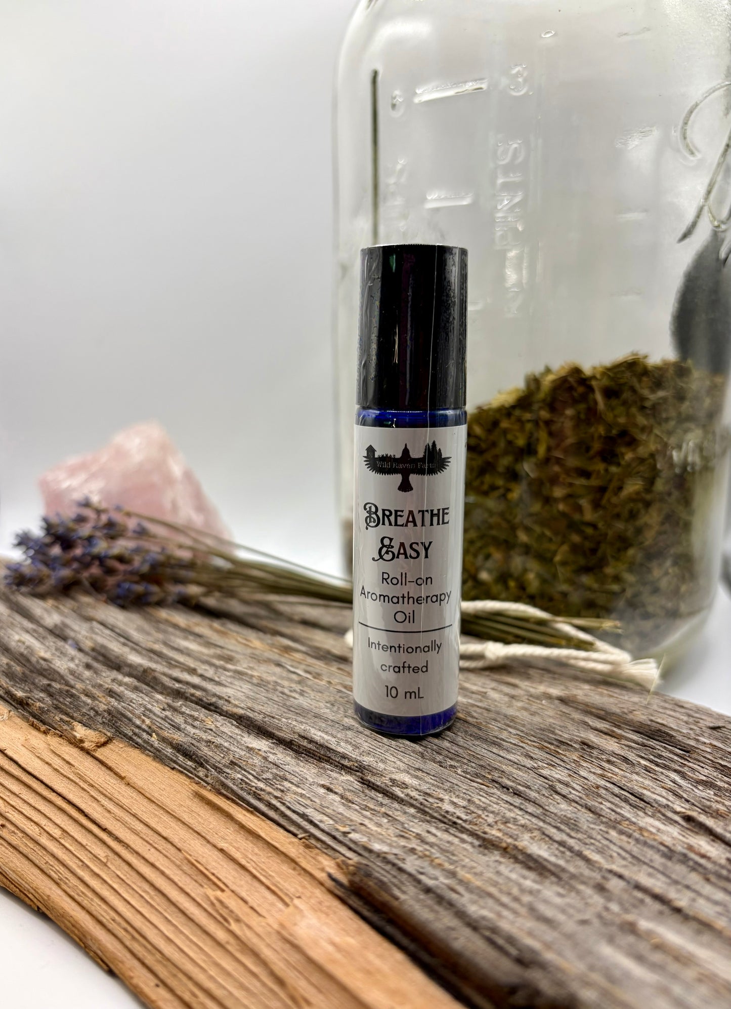 Roll-on aromatherapy oil bottle labeled 'Breathe Easy' on a wooden surface with dried herbs and flowers.
