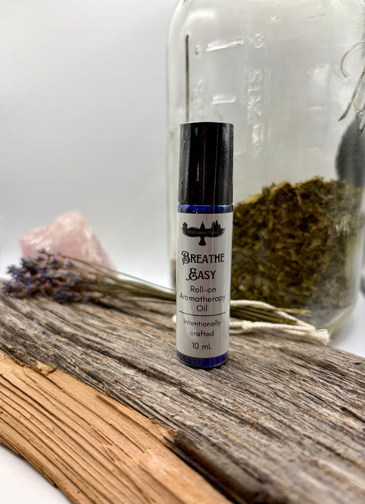 Roll-on aromatherapy oil bottle labeled 'Breathe Easy' on a wooden surface with dried herbs and flowers.