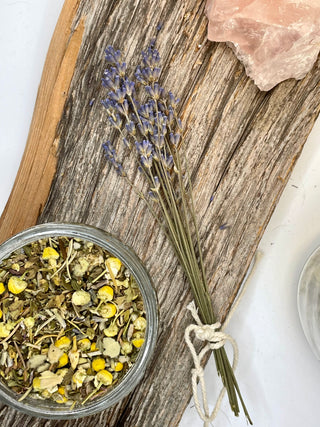 Herbs in a glass bowl with dried lavender on a wooden board