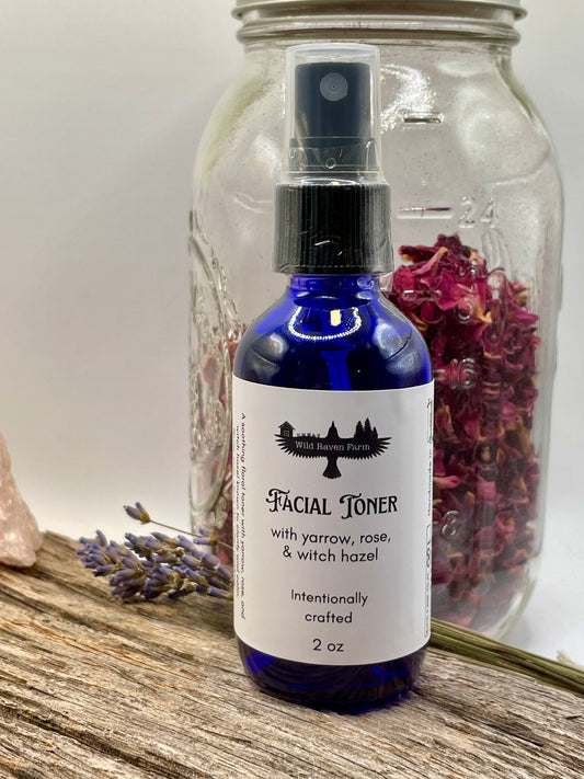 Facial toner bottle with label on a wooden surface with dried flowers and a jar in the background.