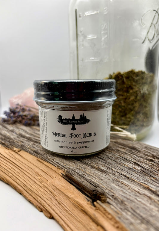Jar of herbal foot scrub with a jar of herbs in the background on a wooden surface.
