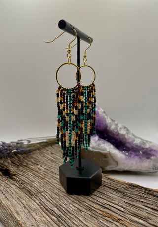 Beaded earrings on a stand with a crystal formation in the background