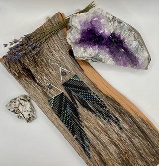 Beaded earrings on a wooden surface with a crystal and lavender.