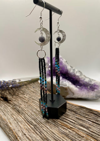 Pair of beaded earrings on a stand with a crystal in the background