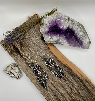 Pair of beaded earrings on a wooden surface with an amethyst crystal and lavender.