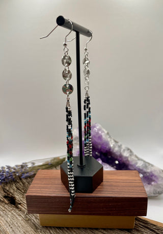 Pair of beaded earrings on a wooden stand with a light background