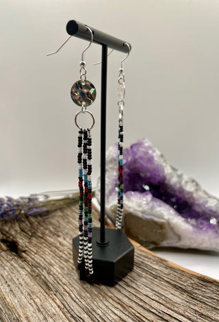 Beaded earrings on a stand with a crystal formation in the background