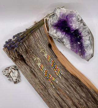 Earrings with colorful beads on a wooden surface with crystals and lavender.