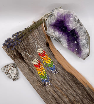 Rainbow beaded earrings on a wooden surface with crystals and lavender.