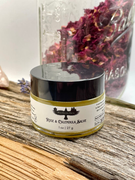 Jar of Rose & Calendula Salve on a wooden surface with dried flowers in the background