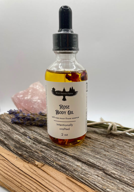 Rose body oil bottle with a dropper on a wooden surface with lavender and a crystal in the background.