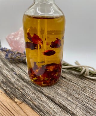 Bottle of oil with dried rose petals on a wooden surface