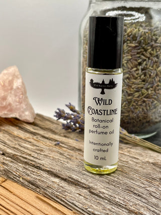 Roll-on perfume oil bottle labeled 'Wild Coastline' on a wooden surface with lavender and a crystal.