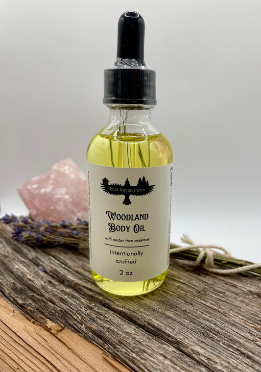Bottle of Woodland Body Oil on a wooden surface with lavender and a crystal in the background