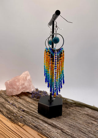 Colorful beaded earrings on a stand with a neutral background