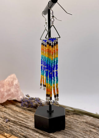 Colorful beaded earrings on a stand with a neutral background