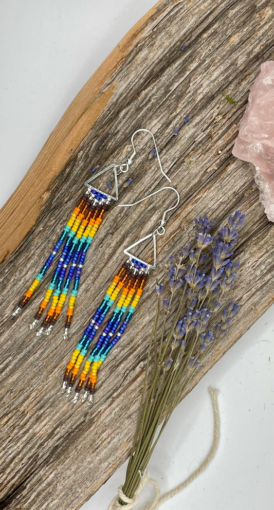 Beaded earrings with colorful beads on a wooden surface with lavender.
